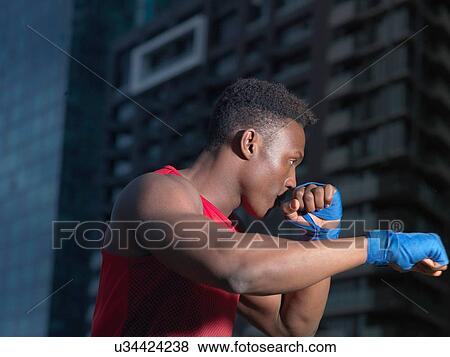 Stock Photo - Portrait of boxer throwing punch, building in background. Fotosearch