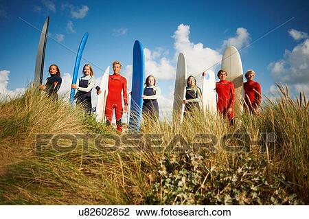 Portrait of group of surfers standing on beach, holding surfboards View Large Photo Image Stock Image - Portrait of group of surfers standing on beach, holding surfboards. Fotosearch