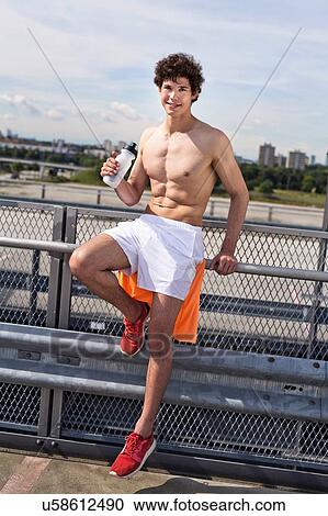 Stock Image - Portrait of young male runner with water bottle taking a break. Fotosearch