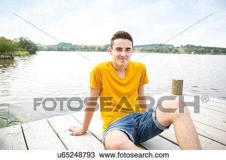 Portrait of young man sitting on jetty View Large Photo Image Stock Image - Portrait of young man sitting on jetty. Fotosearch
