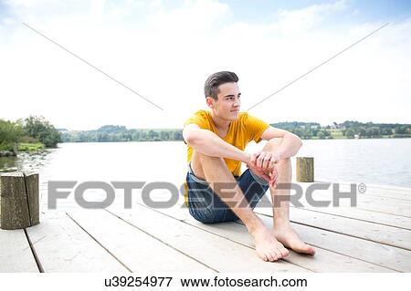 Portrait of young man sitting on jetty View Large Photo Image Stock Photo - Portrait of young man sitting on jetty. Fotosearch