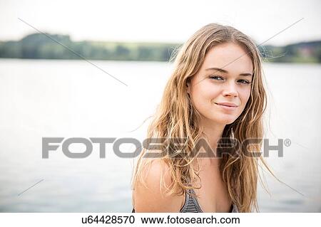 Stock Image - Portrait of young woman beside lake. Fotosearch