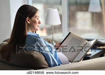Pregnant woman sitting on sofa, reading book View Large Photo Image Stock Photograph - Pregnant woman sitting on sofa, reading book. Fotosearch