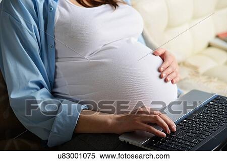 Pregnant woman sitting on sofa, using laptop, mid section View Large Photo Image Stock Photography - Pregnant woman sitting on sofa, using laptop, mid section. Fotosearch