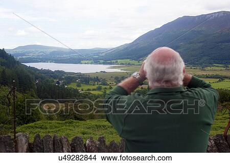 Picture - Rear view of man birdwatching at viewpoint between Braithwaite Village and Whinlatter, Cumbria, UK. Fotosearch