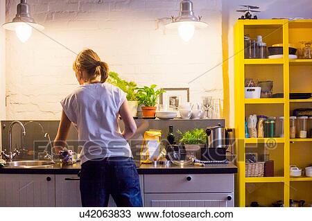Stock Image - Rear view of mid adult woman preparing to bake at kitchen counter. Fotosearch