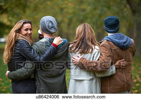 Stock Photograph - Rear view of two young couples walking in autumn park. Fotosearch