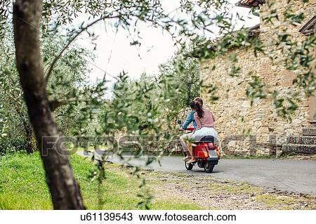 Rear view of young couple riding moped in village, Florence, Italy View Large Photo Image Stock Image - Rear view of young couple riding moped in village, Florence, Italy. Fotosearch