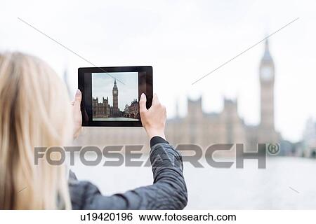 Rear view of young woman photographing Big Ben on digital tablet, London, England, UK View Large Photo Image Stock Photograph - Rear view of young woman photographing Big Ben on digital tablet, London, England, UK. Fotosearch