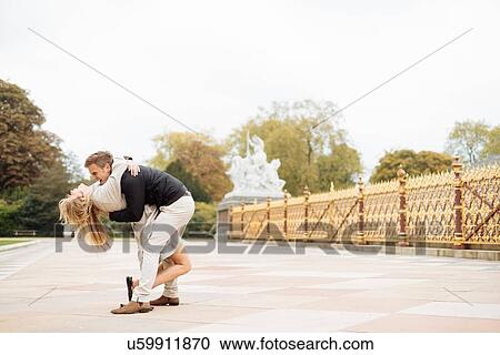 Stock Image - Romantic young couple bending over whilst hugging. Fotosearch