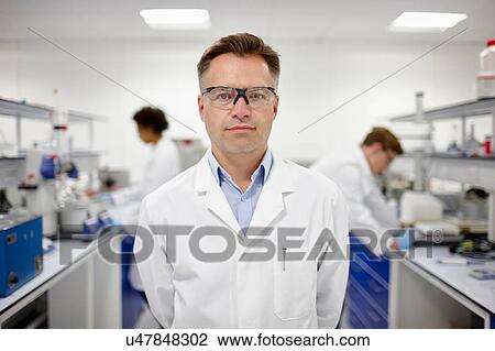 Scientist in laboratory, colleagues working in background View Large Photo Image Stock Image - Scientist in laboratory, colleagues working in background. Fotosearch
