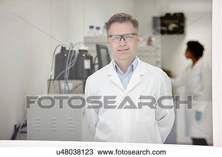 Scientist smiling in laboratory, colleague working in background View Large Photo Image Stock Image - Scientist smiling in laboratory, colleague working in background. Fotosearch