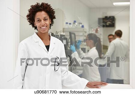 Scientist smiling in laboratory, colleagues working in background View Large Photo Image Stock Image - Scientist smiling in laboratory, colleagues working in background. Fotosearch