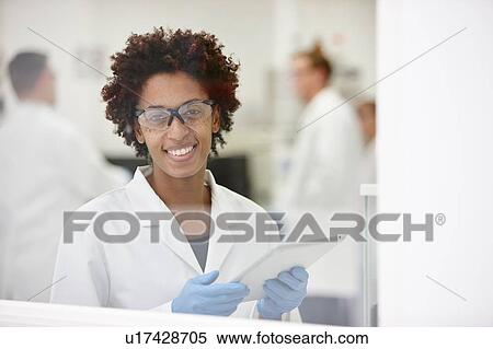 Scientist smiling in laboratory, colleagues working in background View Large Photo Image Stock Photography - Scientist smiling in laboratory, colleagues working in background. Fotosearch