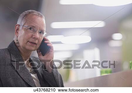 Senior businesswoman chatting on smartphone in hotel lobby View Large Photo Image Stock Image - Senior businesswoman chatting on smartphone in hotel lobby. Fotosearch