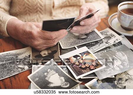 Senior woman sitting at table, looking through old photographs, mid section View Large Photo Image Stock Photography - Senior woman sitting at table, looking through old photographs, mid section. Fotosearch