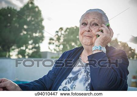 Stock Photo - Senior woman using smartphone in backyard. Fotosearch