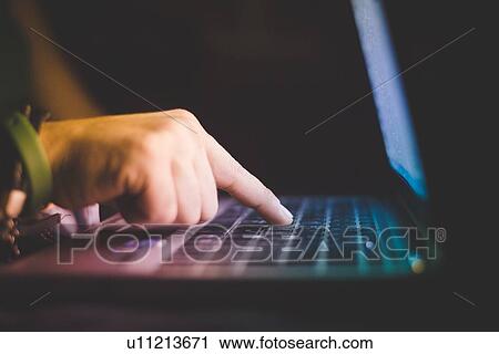Stock Image - Side view of hand typing on laptop computer keyboard. Fotosearch