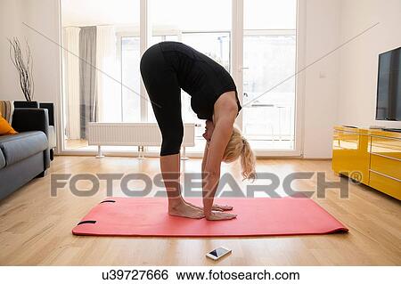 Side view of mature woman in lounge on yoga mat bending over touching floor View Large Photo Image Stock Photograph - Side view of mature woman in lounge on yoga mat bending over touching floor. Fotosearch