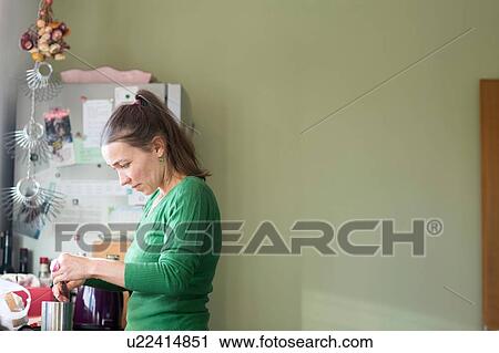 Side view of mid adult woman in kitchen making a cup of tea, looking down View Large Photo Image Stock Image - Side view of mid adult woman in kitchen making a cup of tea, looking down. Fotosearch