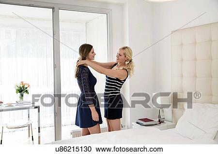 Side view of woman in bedroom helping friend wearing dress to get ready View Large Photo Image Stock Image - Side view of woman in bedroom helping friend wearing dress to get ready. Fotosearch