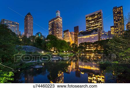 Stock Image - Skyline in reflection lake in Central Park at night, New York, USA. Fotosearch