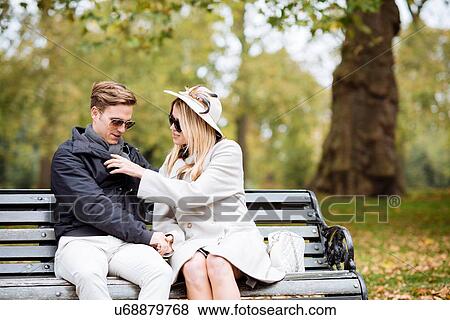 Stock Photo - Stylish young couple sitting on park bench, London, England, UK. Fotosearch
