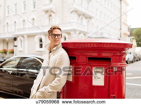 Stylish young man leaning against red post box, London, England, UK View Large Photo Image Stock Photo - Stylish young man leaning against red post box, London, England, UK. Fotosearch