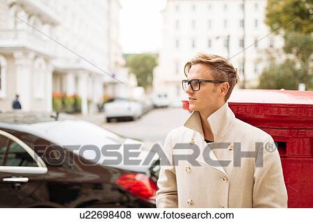 Stock Photo - Stylish young man next to red post box, London, England, UK. Fotosearch