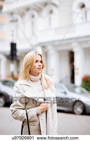 Stock Image - Stylish young woman waiting on street, London, England, UK. Fotosearch