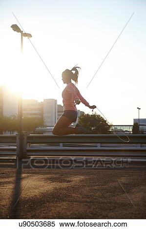 Sunlit silhouette of young female skipping on rooftop View Large Photo Image Stock Photography - Sunlit silhouette of young female skipping on rooftop. Fotosearch