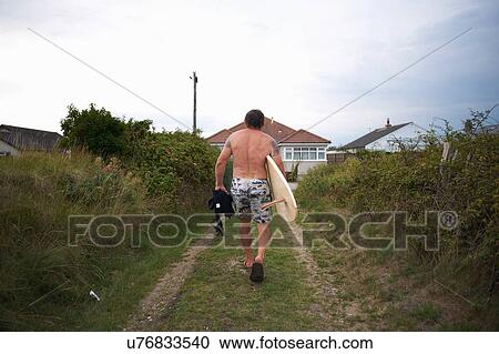Stock Image - Surfer carrying surfboard home. Fotosearch