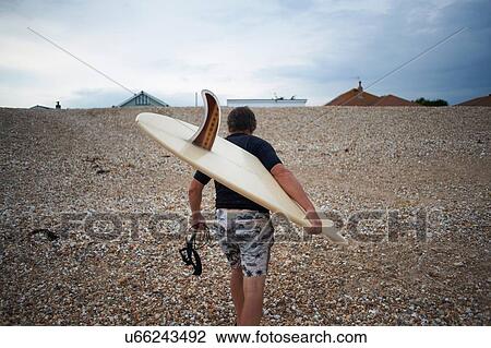 Surfer carrying surfboard on beach View Large Photo Image Stock Image - Surfer carrying surfboard on beach. Fotosearch