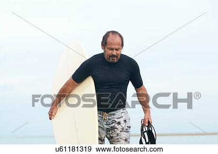 Surfer carrying surfboard View Large Photo Image Stock Photo - Surfer carrying surfboard. Fotosearch