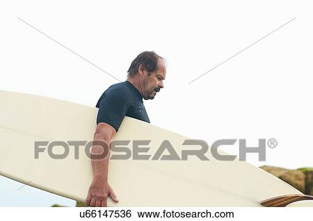 Stock Photograph - Surfer carrying surfboard. Fotosearch