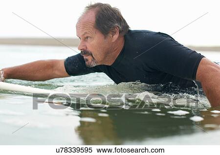 Stock Photography - Surfer paddling surfboard out to sea. Fotosearch