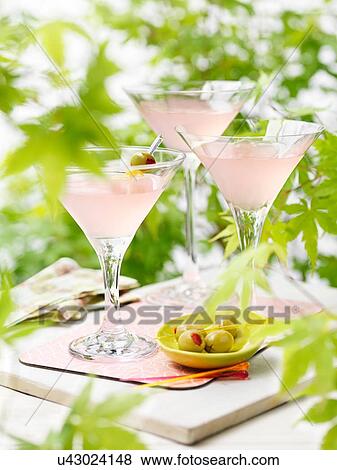Three glasses of pink grapefruit and martini cocktails with green olives View Large Photo Image Stock Photo - Three glasses of pink grapefruit and martini cocktails with green olives. Fotosearch