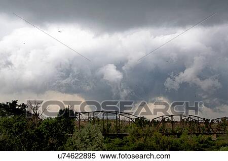 Stock Photography - Tornado behind railroad bridge, birds flying around the funnel, Canadian, Texas, USA. Fotosearch