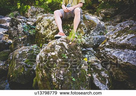 Stock Photo - Tourist sitting on rocks, Garda, Italy. Fotosearch