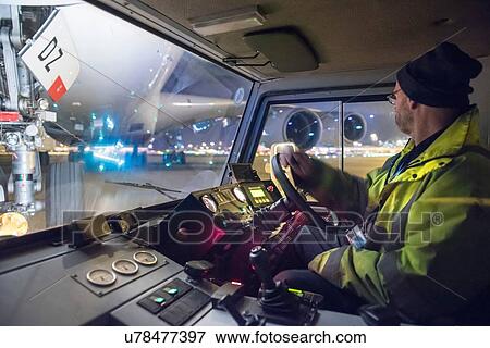 Stock Photo - Tug driver moving A380 aircraft on runway at night. Fotosearch