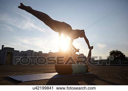 Two silhouetted young women practicing yoga in urban parking lot View Large Photo Image Stock Image - Two silhouetted young women practicing yoga in urban parking lot. Fotosearch