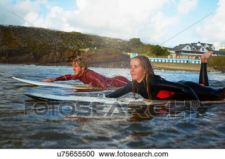 Two surfers paddling on surfboards View Large Photo Image Stock Image - Two surfers paddling on surfboards. Fotosearch