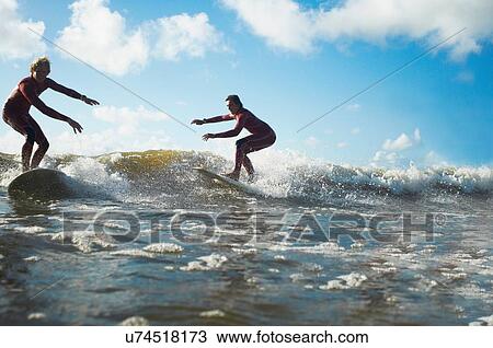 Two surfers riding wave View Large Photo Image Stock Image - Two surfers riding wave. Fotosearch