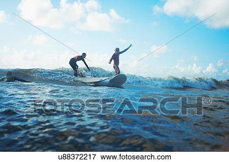 Two surfers surfing in sea View Large Photo Image Stock Photo - Two surfers surfing in sea. Fotosearch
