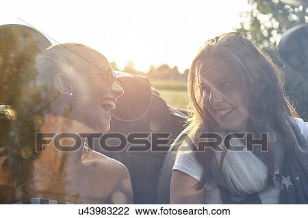 Two young female friends chatting in convertible car View Large Photo Image Stock Image - Two young female friends chatting in convertible car. Fotosearch