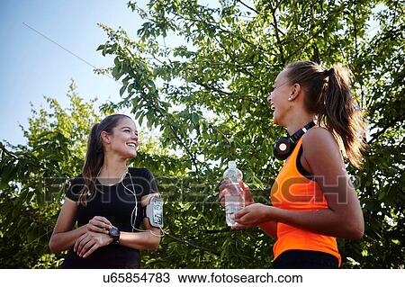 Stock Image - Two young female runners chatting in park. Fotosearch