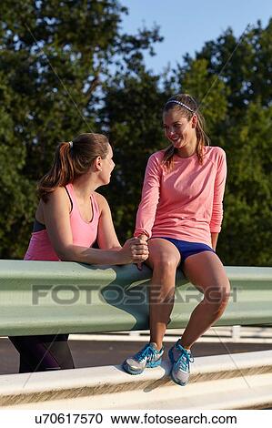 Stock Image - Two young female runners chatting in parking lot. Fotosearch
