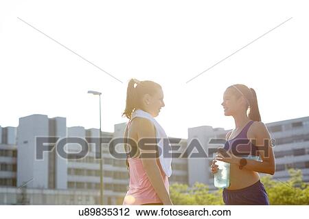 Two young female runners chatting on urban rooftop View Large Photo Image Stock Image - Two young female runners chatting on urban rooftop. Fotosearch
