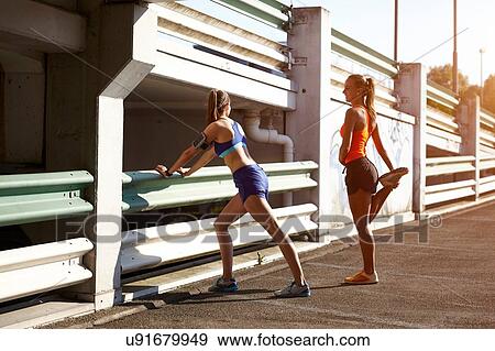 Stock Photo - Two young female runners warming up in parking lot. Fotosearch