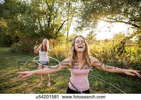 Two young girls in rural environment, fooling around, using hula hoops, View Large Photo Image Stock Image - Two young girls in rural environment, fooling around, using hula hoops,. Fotosearch